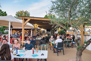 Terrace of the restaurant bar at Les Rivières campsite with parasols