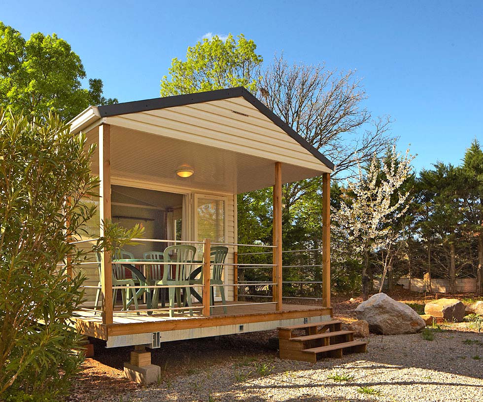Mobil-home et sa terrasse en bois dans le parc du camping Les Rivières